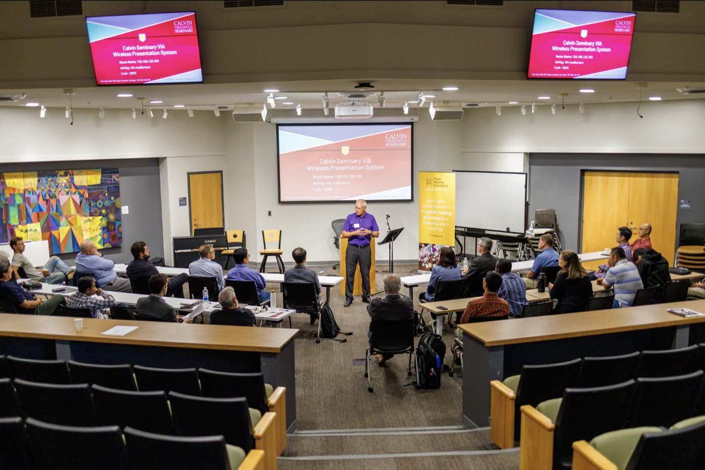 A speaker addressing participants in a Calvin Theological Seminary lecture hall.