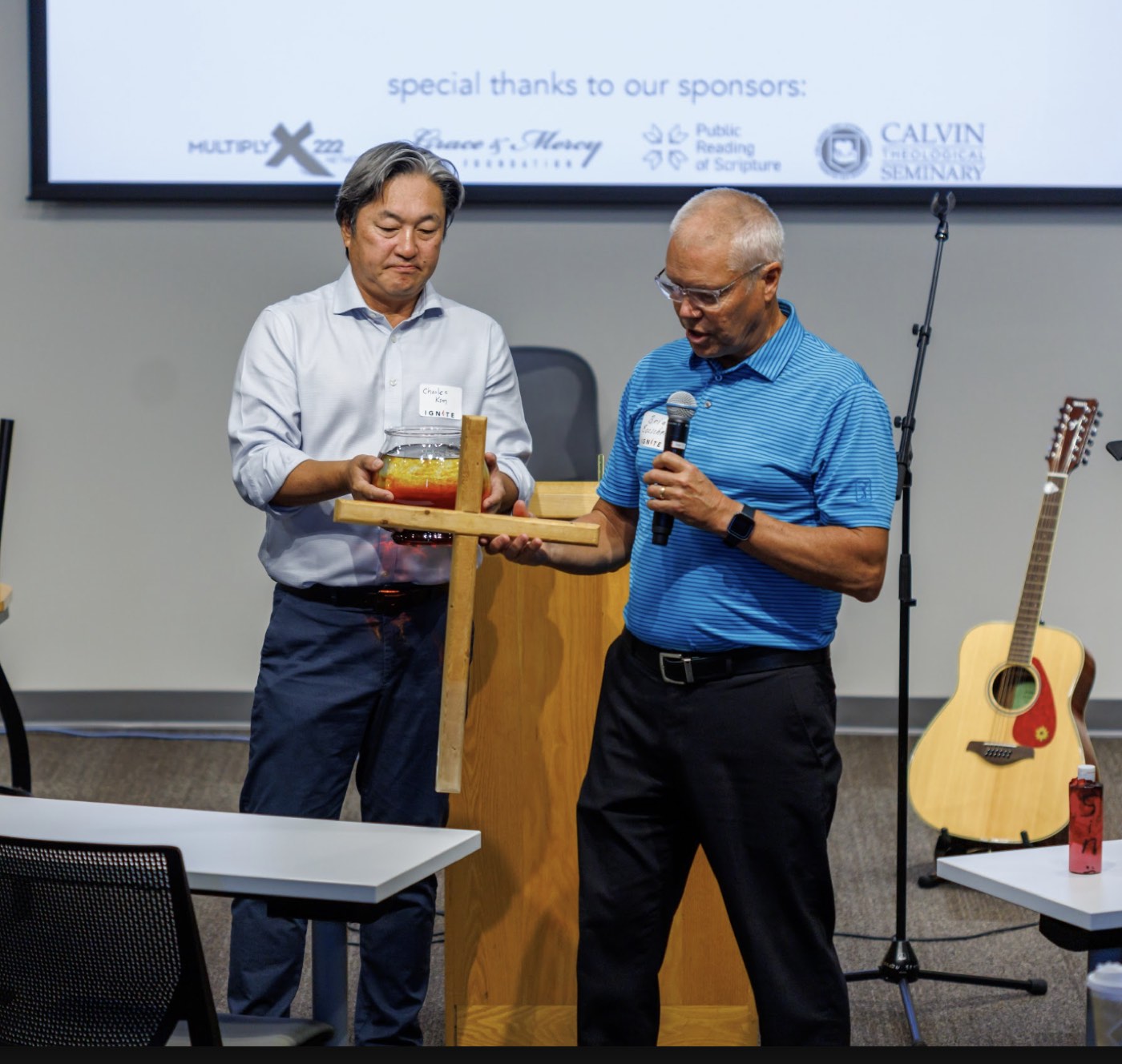 Two ministry leaders holding a wooden cross during a gathering.