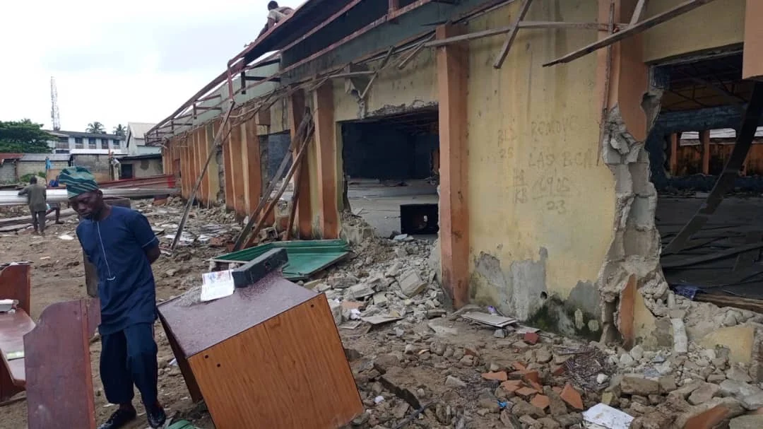 The outside of a church building with open wall sections, exposed roof supports, and rubble on the ground.