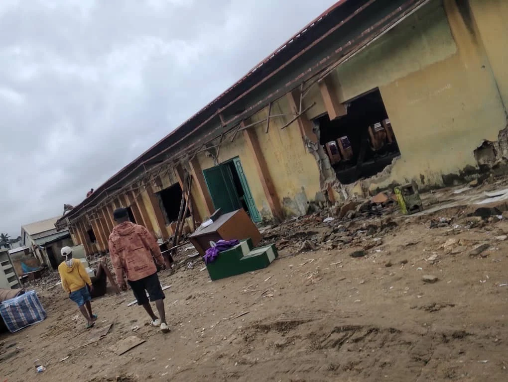 People walking beside a church building with openings in the walls and materials outside.