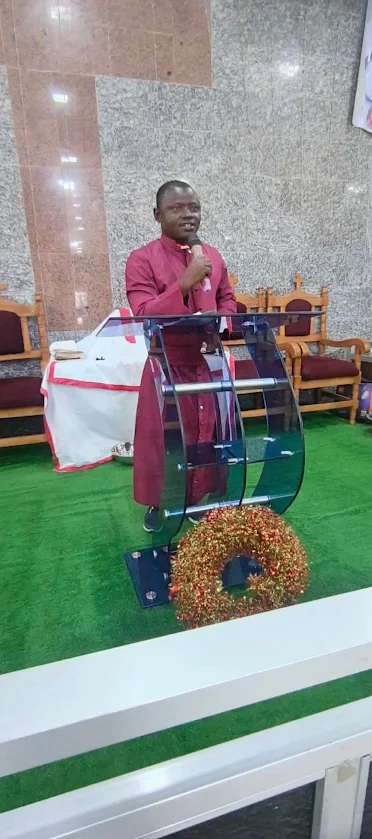 A pastor speaking into a microphone at a lectern in the Lagos church before demolition