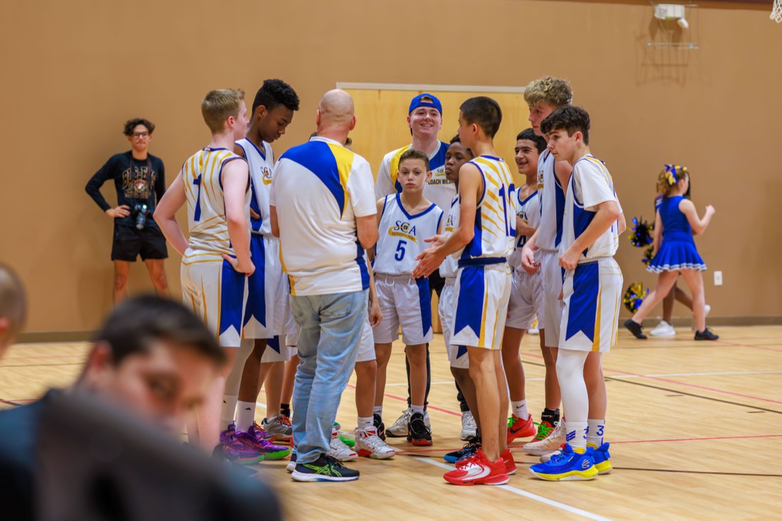 Sunlight Academy basketball players gathered around their coach on the court.