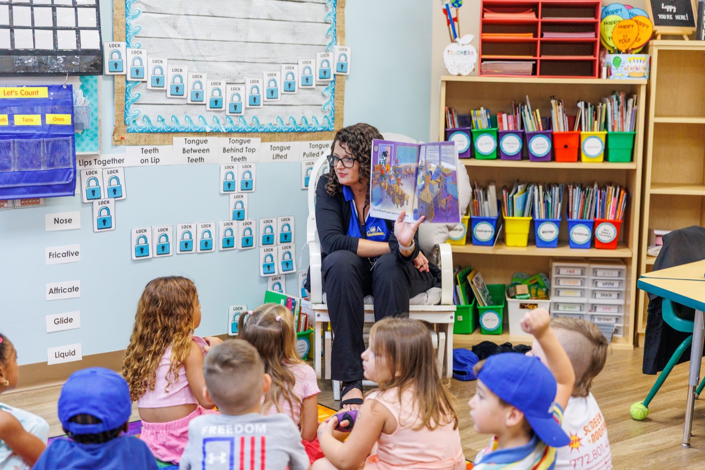 A Sunlight Academy teacher reading with children gathered in her classroom.
