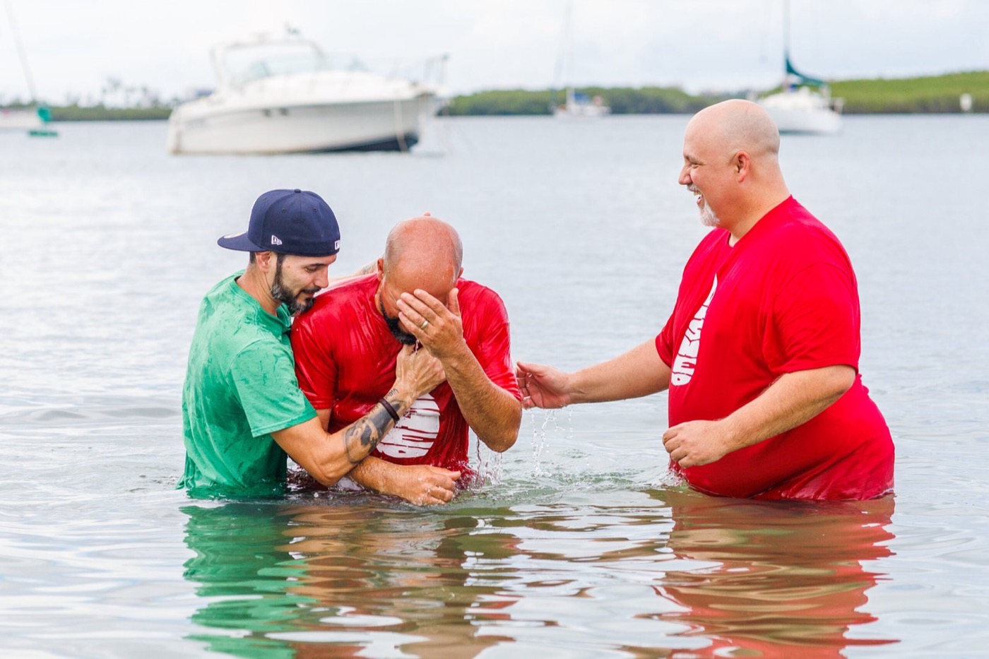 A Sunlight baptism celebration in the water, with two people supporting the person being baptized.