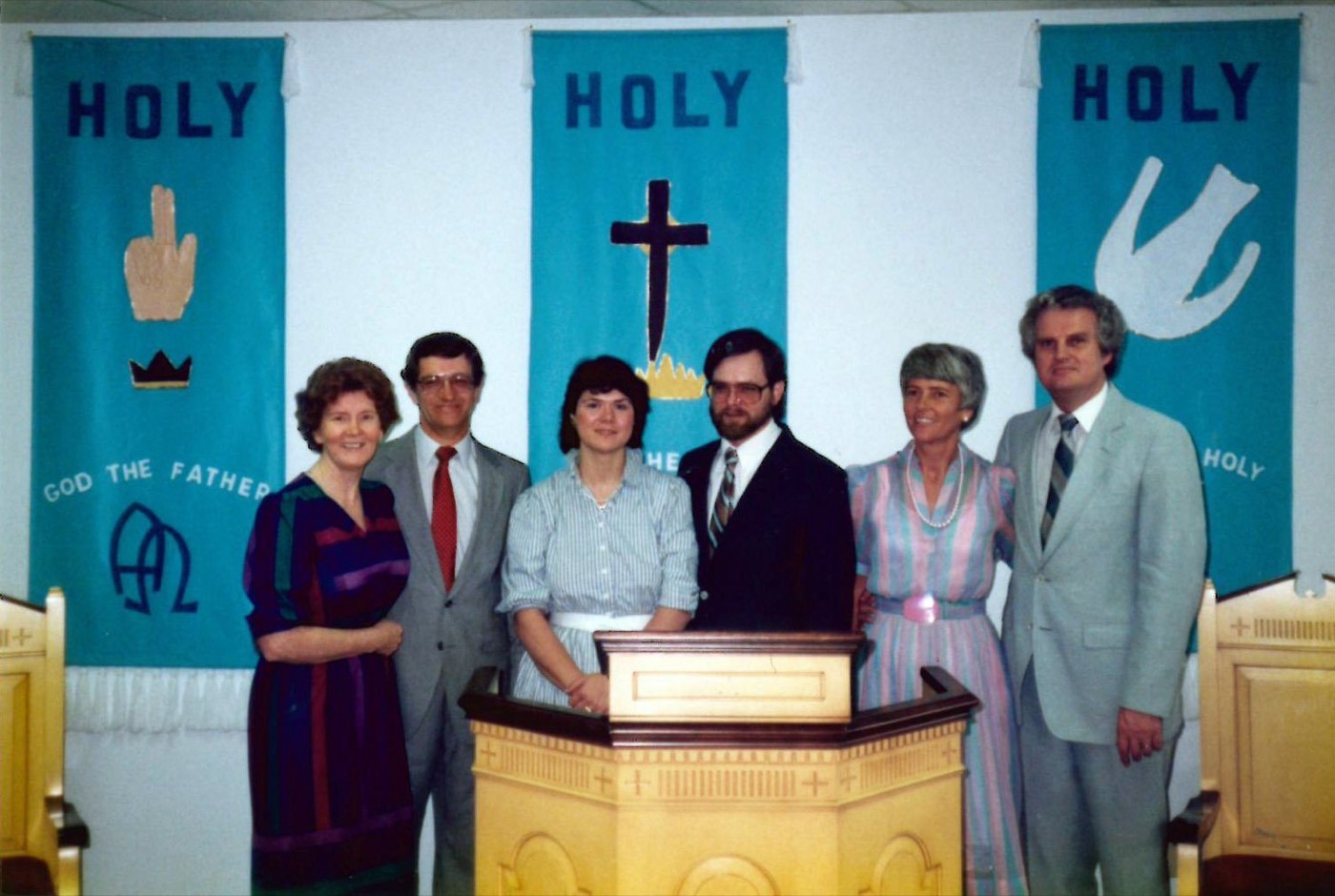 An archival photograph of six people gathered near a church pulpit.